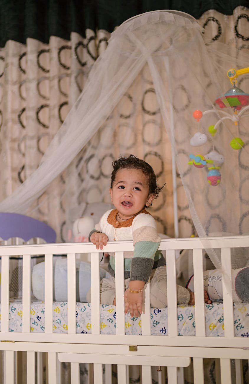 a smiling toddler on the white crib