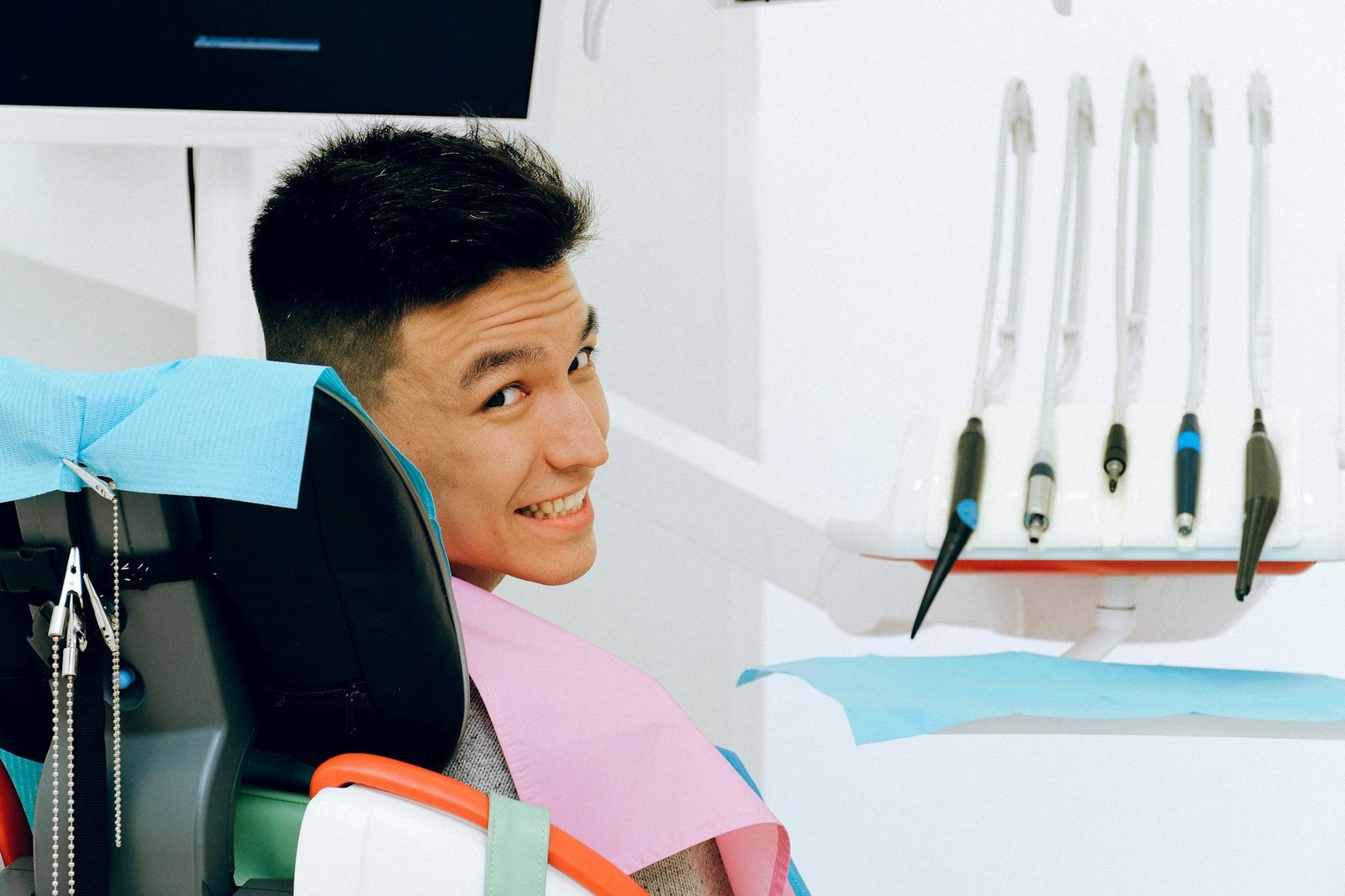 cheerful ethnic man sitting in dental chair in modern dentist office